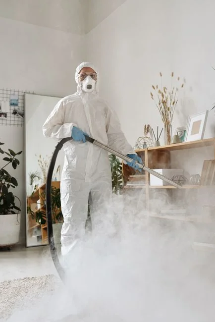 Primer plano de unas manos con guantes rosas usando una botella de spray y un paño en interiores.